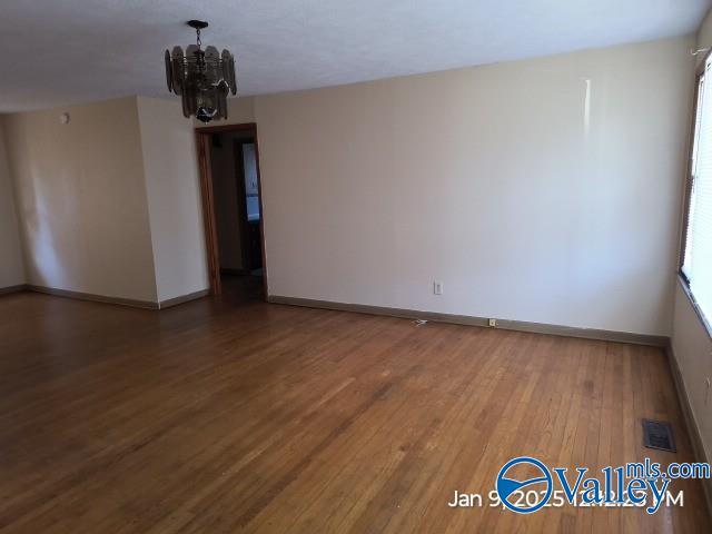 unfurnished room featuring a notable chandelier and wood-type flooring