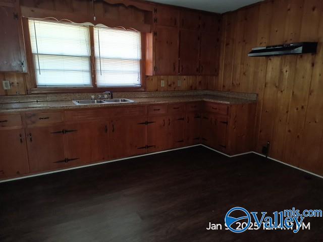 kitchen featuring wood walls and sink