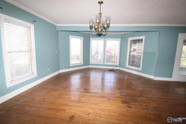 unfurnished dining area with hardwood / wood-style floors, ornamental molding, a textured ceiling, and an inviting chandelier