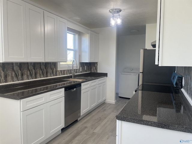 kitchen featuring light wood-style flooring, stainless steel appliances, a sink, decorative backsplash, and washer / dryer