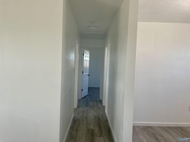 hall with attic access, baseboards, and wood finished floors