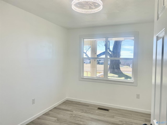 empty room with baseboards, visible vents, and wood finished floors