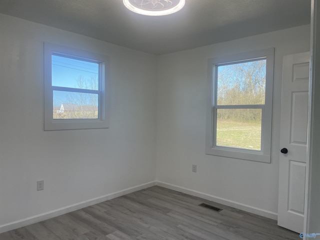 empty room featuring visible vents, baseboards, and wood finished floors