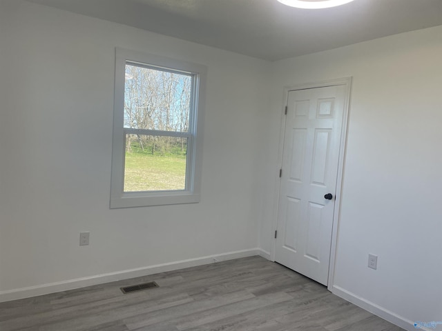 spare room featuring wood finished floors, visible vents, and baseboards