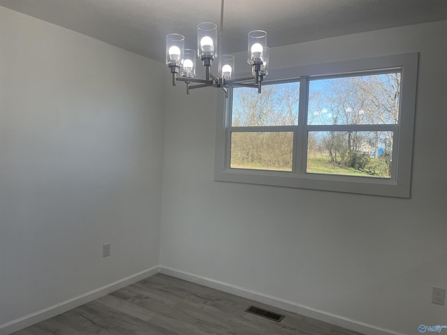 unfurnished dining area featuring visible vents, baseboards, and wood finished floors