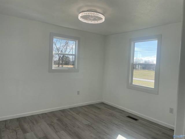 empty room featuring wood finished floors, visible vents, and baseboards