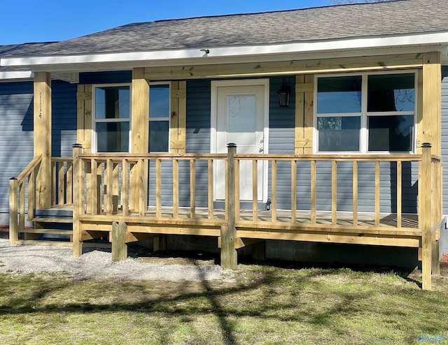 view of exterior entry featuring covered porch and roof with shingles