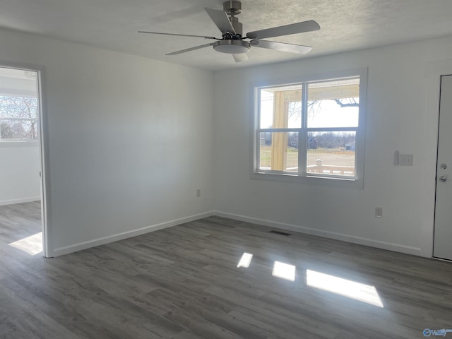 empty room featuring dark wood-style flooring, a healthy amount of sunlight, and baseboards