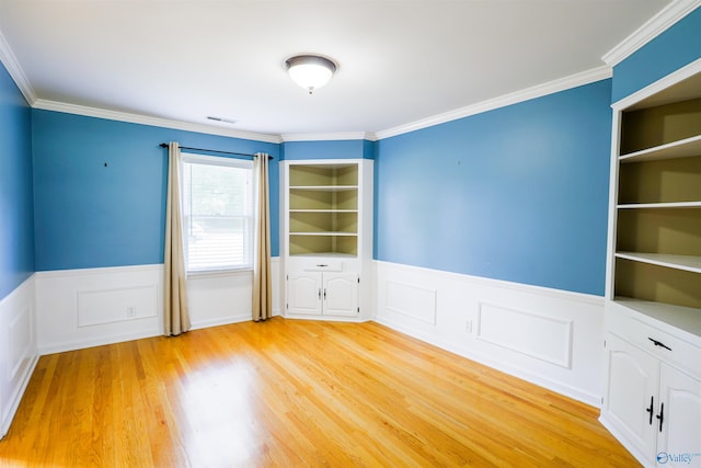 unfurnished room with a wainscoted wall, light wood finished floors, and crown molding