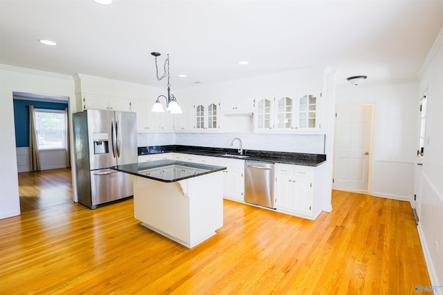 kitchen with appliances with stainless steel finishes, ornamental molding, white cabinets, a center island, and dark countertops