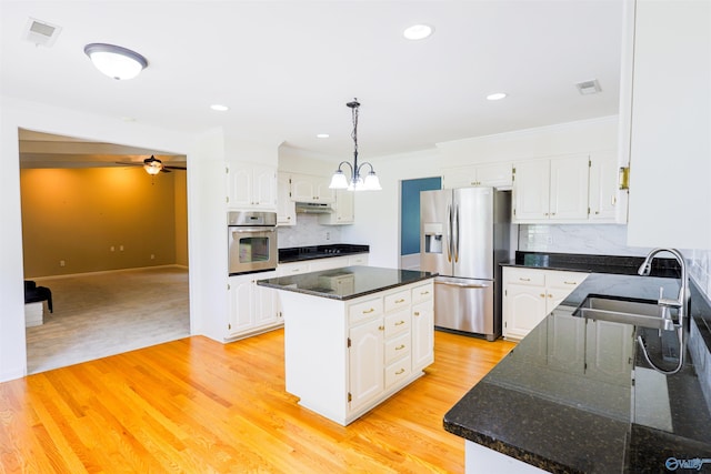 kitchen with appliances with stainless steel finishes, a sink, under cabinet range hood, a center island, and crown molding