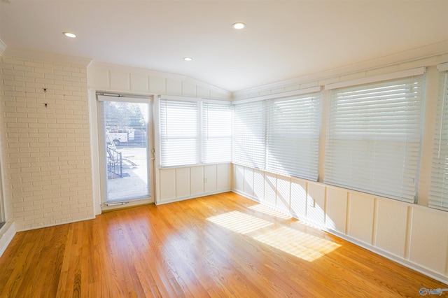 empty room with ornamental molding, a decorative wall, wood finished floors, brick wall, and recessed lighting