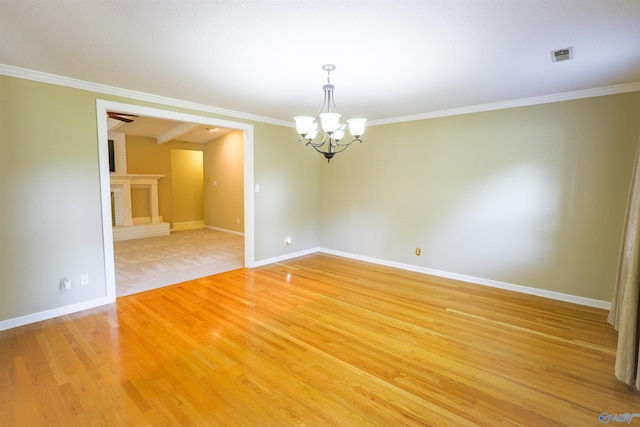 spare room featuring a chandelier, baseboards, ornamental molding, and light wood finished floors