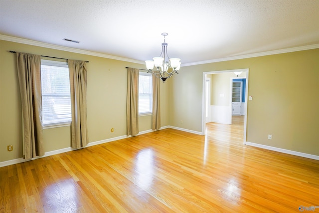 spare room with a chandelier, light wood finished floors, ornamental molding, and baseboards