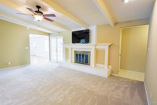 unfurnished living room with carpet, beamed ceiling, a fireplace, a ceiling fan, and baseboards
