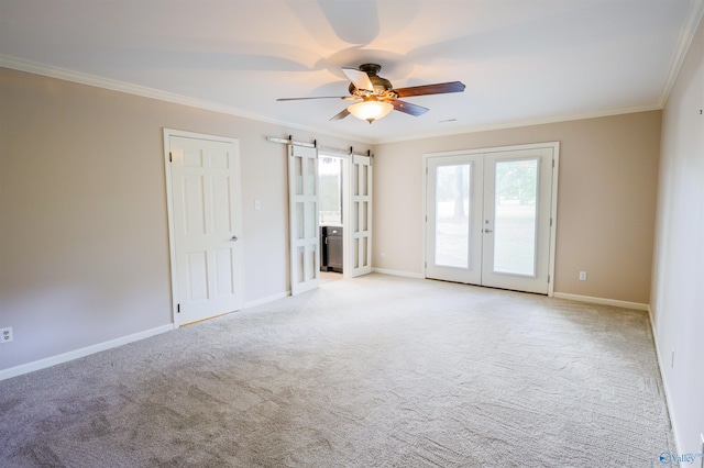 spare room with french doors, a ceiling fan, ornamental molding, light carpet, and a barn door