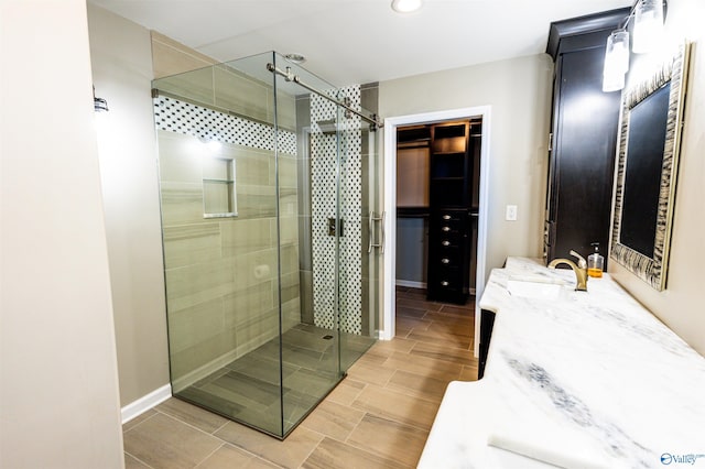 full bath with a stall shower, vanity, baseboards, and wood finish floors