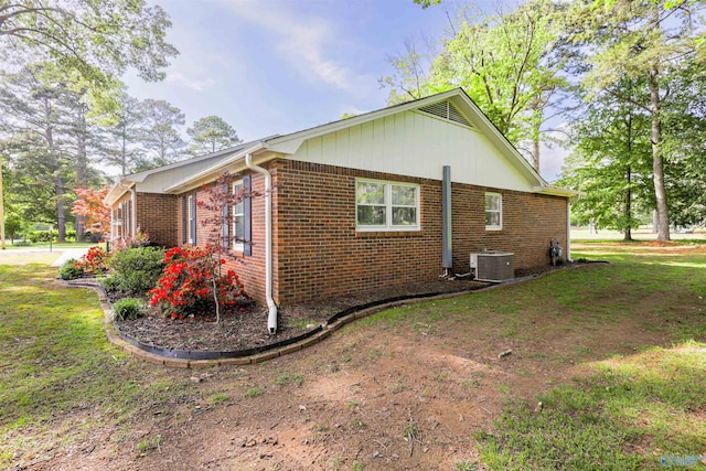 view of property exterior featuring central AC unit, brick siding, and a yard