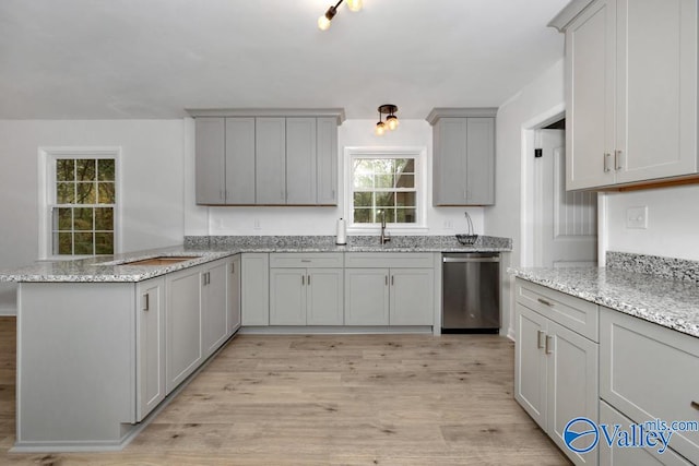 kitchen with light hardwood / wood-style floors, light stone counters, dishwasher, sink, and gray cabinetry