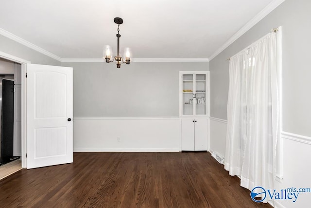 empty room featuring dark hardwood / wood-style floors, an inviting chandelier, and ornamental molding