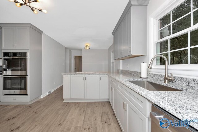 2512 Vista Dr SE, Huntsville, AL 35803 - kitchen featuring stainless steel appliances, a sink, gray cabinetry, light wood-style flooring, and a peninsula