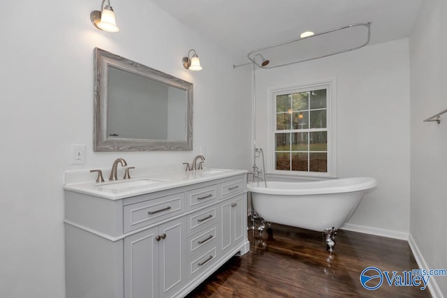 bathroom featuring wood-type flooring, a tub to relax in, and vanity