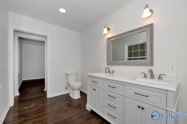 bathroom with toilet, vanity, and wood-type flooring