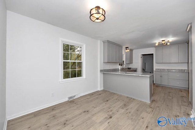 kitchen featuring kitchen peninsula, light hardwood / wood-style floors, sink, and gray cabinetry