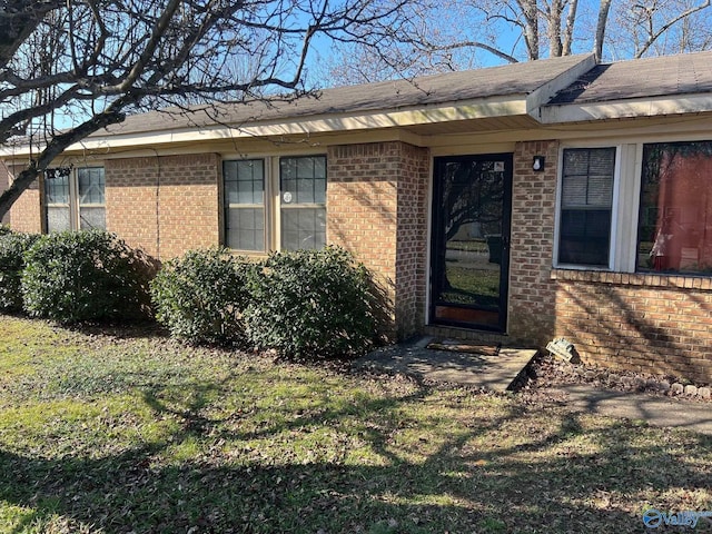 property entrance with a yard and brick siding