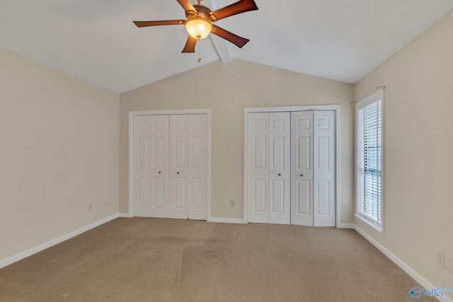 unfurnished bedroom featuring multiple windows, ceiling fan, light colored carpet, and vaulted ceiling with beams