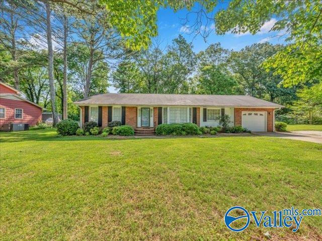 ranch-style home with concrete driveway, a garage, a front lawn, and brick siding