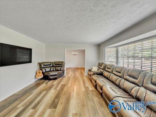 living area with a chandelier, wood finished floors, and a textured ceiling