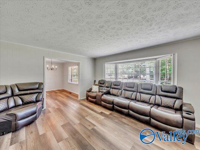 living room with a chandelier, a textured ceiling, and wood finished floors