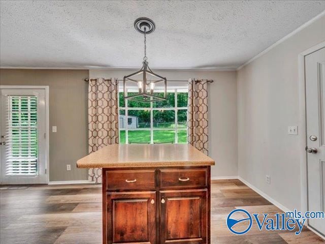 kitchen featuring a chandelier, a textured ceiling, wood finished floors, light countertops, and baseboards
