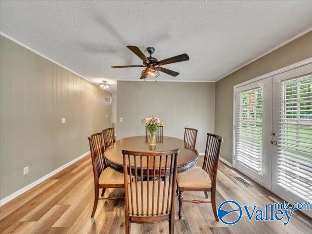 dining space with crown molding, light wood finished floors, french doors, a textured ceiling, and baseboards