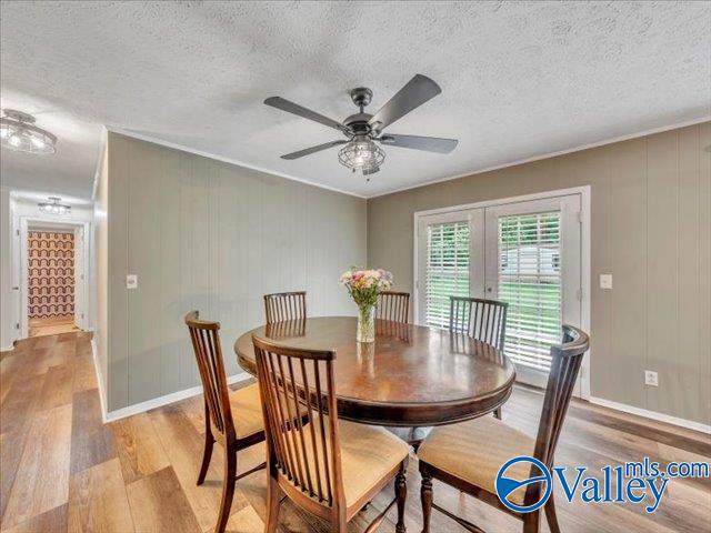 dining area featuring light wood-style floors, french doors, a ceiling fan, a textured ceiling, and baseboards