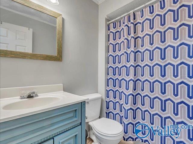 bathroom featuring toilet, vanity, ornamental molding, and curtained shower