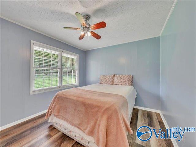 bedroom featuring wood finished floors, a textured ceiling, baseboards, and a ceiling fan
