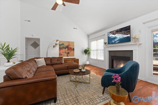 living room with hardwood / wood-style flooring, ceiling fan, high vaulted ceiling, and a fireplace