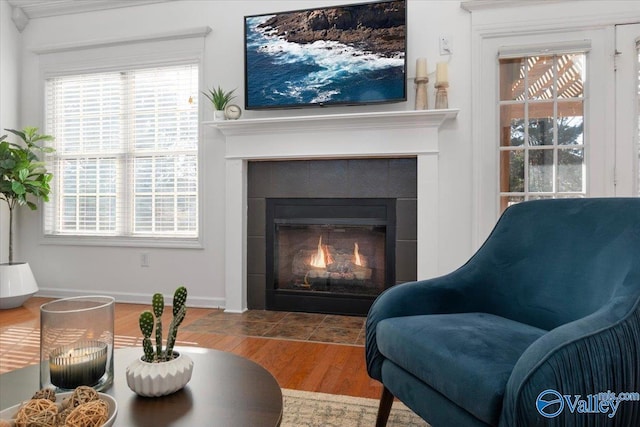 sitting room with a tiled fireplace, plenty of natural light, and wood-type flooring