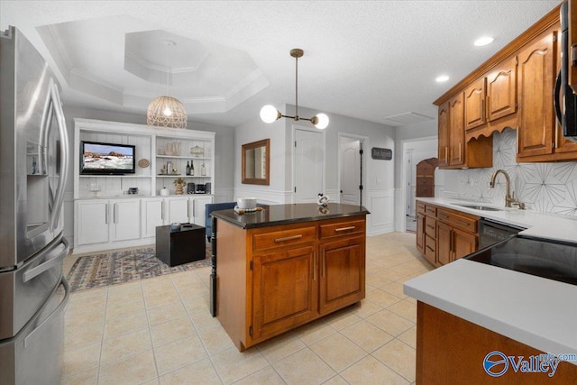 kitchen with pendant lighting, sink, a tray ceiling, a kitchen island, and stainless steel fridge with ice dispenser