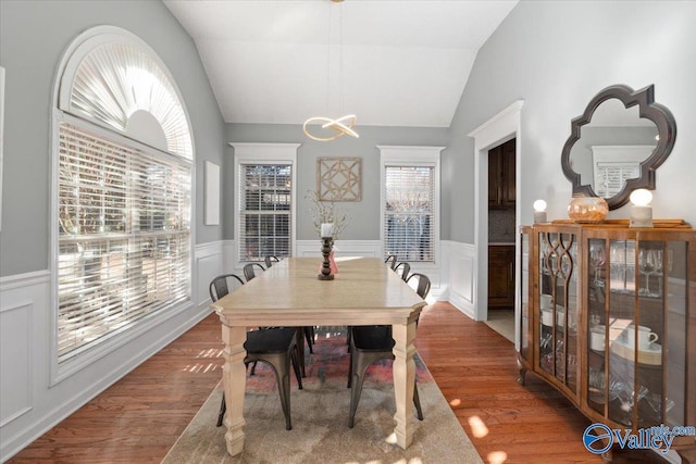 dining area with hardwood / wood-style flooring, vaulted ceiling, and a notable chandelier