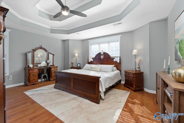 bedroom featuring crown molding, a textured ceiling, a raised ceiling, hardwood / wood-style flooring, and ceiling fan