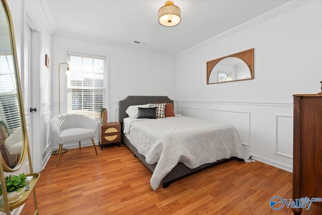 bedroom featuring crown molding, a textured ceiling, and light wood-type flooring