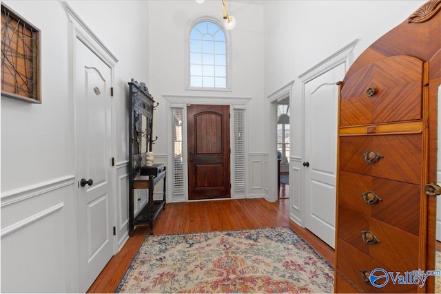 foyer entrance featuring a towering ceiling and light wood-type flooring