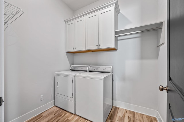 clothes washing area with cabinets, light hardwood / wood-style floors, and independent washer and dryer