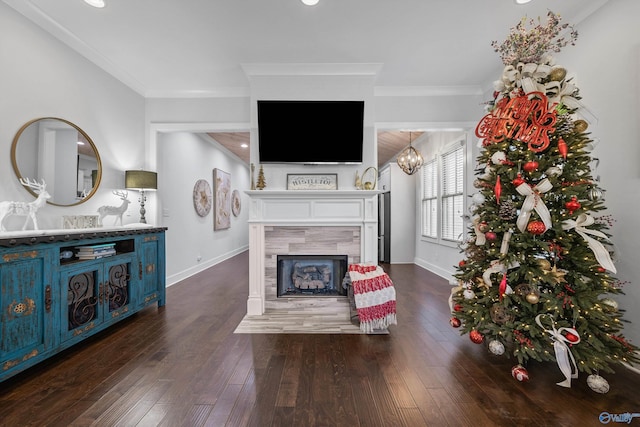 living room featuring a tiled fireplace, dark wood-type flooring, and ornamental molding