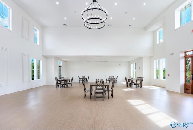 dining space with light hardwood / wood-style floors, a high ceiling, and a notable chandelier