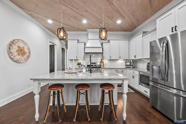 kitchen with hanging light fixtures, an island with sink, appliances with stainless steel finishes, and light stone countertops