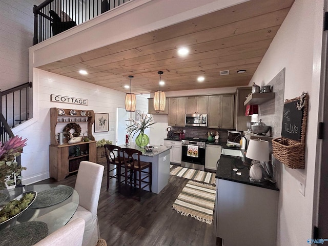 kitchen with appliances with stainless steel finishes, dark hardwood / wood-style flooring, tasteful backsplash, decorative light fixtures, and a kitchen island